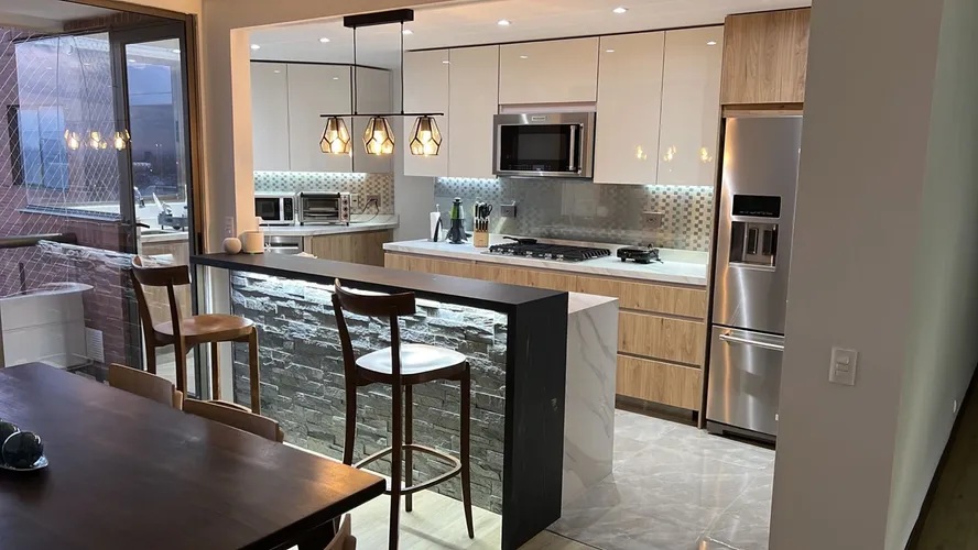 Cocina abierta con isla de mármol e iluminación cálida