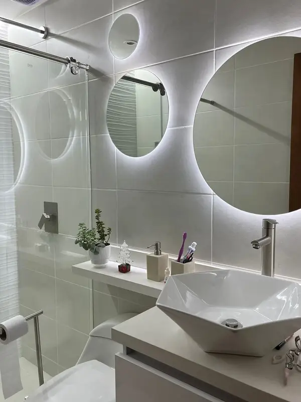 Baño con espejos circulares retroiluminados